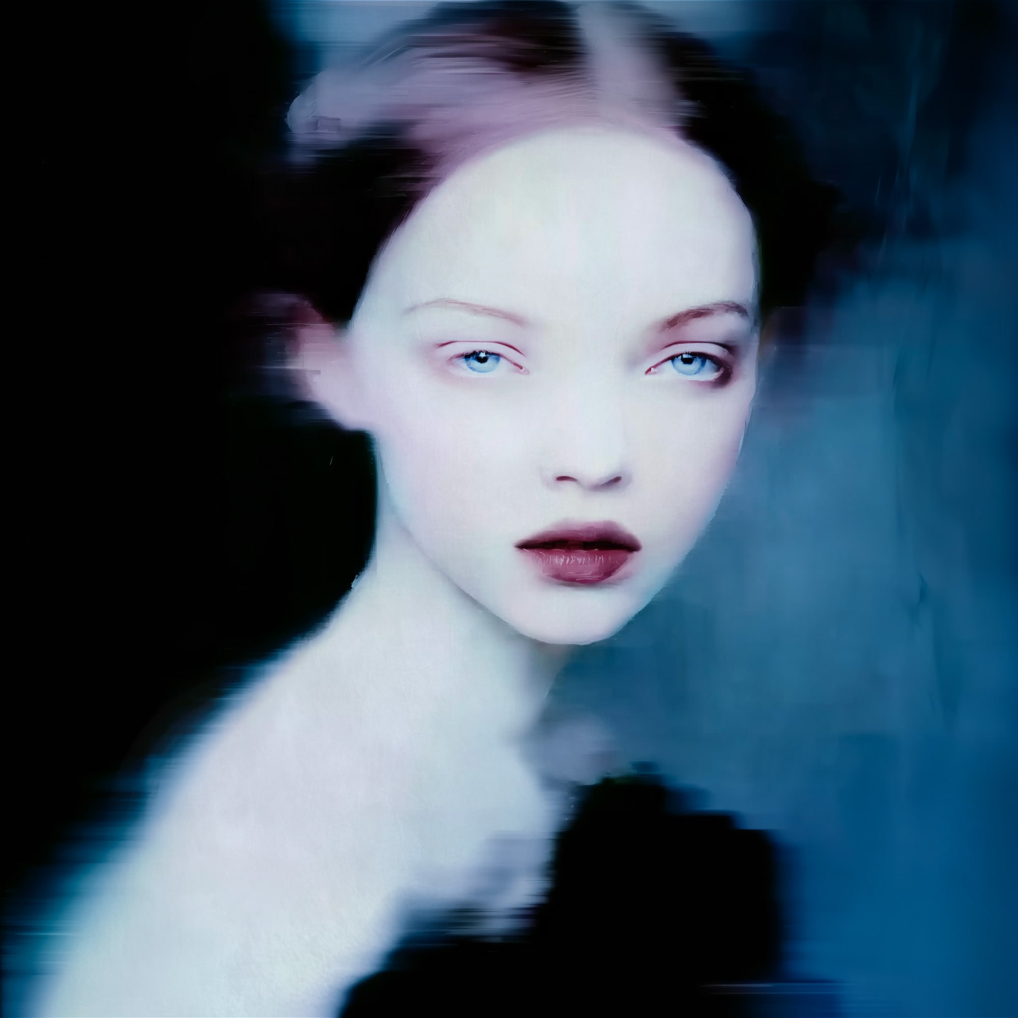 “MEETH 013” by Giuseppe Scarangelli, mixed media on aluminium panel, 150×150 cm, 2025. A large-scale contemporary portrait depicting a young woman with an ethereal, almost translucent complexion. Her features are softly rendered with delicate shading, while blurred contours around her hair and shoulders create a sense of motion and dreamlike atmosphere. The composition uses cool blue, violet, and muted grey tones, contrasted by a dark garment framing the face. The work blends realism with abstraction, giving the figure a haunting, otherworldly presence.